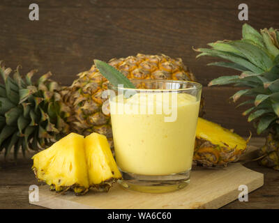 Ananassaft und Ananasscheibe auf einen hölzernen Tisch gelegt. Stockfoto