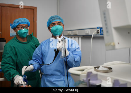 (190818) - CHANGSHA, Aug 18, 2019 (Xinhua) - Arzt Xiao Yangbao (R) trägt auf endoskopische Untersuchungen für einen Patienten bei der Endoskopie Zentrum von Hunan Chest Hospital in Changsha, der Hauptstadt der zentralchinesischen Provinz Hunan, Nov. 14, 2019. Xiao Yangbao, ein 39-jährige Arzt in der Endoskopie Zentrum von Hunan Chest Hospital, arbeitet an einer Tuberkulose Prävention und Behandlung für fast 8 Jahre. Als Arzt Ausführung von Endoskopie, Xiao ist angesichts der höheren Risiken für Tuberkulose und höhere Betrieb Anforderungen an Genauigkeit und Konzentration. Xiao fühlt sich immer everyti erfreut Stockfoto