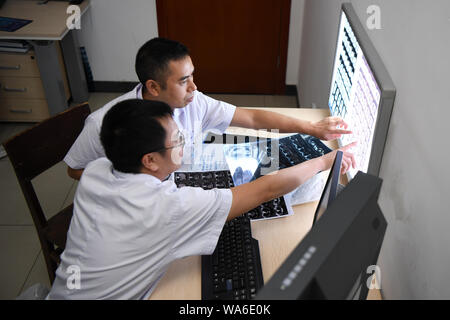 (190818) - CHANGSHA, Aug 18, 2019 (Xinhua) - Arzt Xiao Yangbao (oben) sieht bei X-ray Bilder mit einem Radiologen in der Endoskopie Zentrum von Hunan Chest Hospital in Changsha, der Hauptstadt der zentralchinesischen Provinz Hunan, 15 August, 2019. Xiao Yangbao, ein 39-jährige Arzt in der Endoskopie Zentrum von Hunan Chest Hospital, arbeitet an einer Tuberkulose Prävention und Behandlung für fast 8 Jahre. Als Arzt Ausführung von Endoskopie, Xiao ist angesichts der höheren Risiken für Tuberkulose und höhere Betrieb Anforderungen an Genauigkeit und Konzentration. Xiao fühlt sich immer jedes Mal hi erfreut Stockfoto