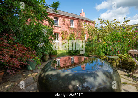 Fishguard, Wales, Großbritannien - 12.August 2019: Kleine reflektierende Brunnen vor der Rosa Hütte der Dyffryn Fernant Garten Stockfoto