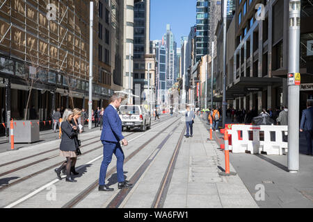 Sydney City Centre Büro Arbeiter auf der George Street im zentralen Geschäftsviertel zu Fuß über abgeschlossen Sydney Light Rail Tracks, Sydney, Australien Stockfoto