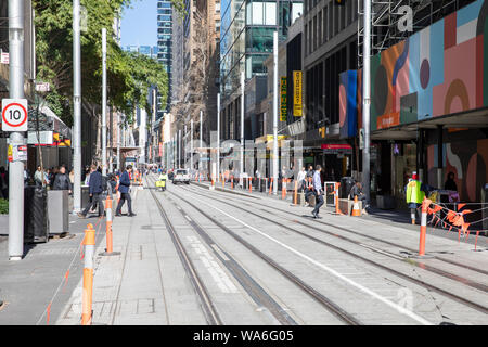 Sydney City Centre Büro Arbeiter auf der George Street im zentralen Geschäftsviertel zu Fuß über abgeschlossen Sydney Light Rail Tracks, Sydney, Australien Stockfoto