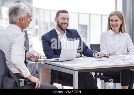 Business Menschen lachen am Arbeitsplatz sitzen an einem Konferenztisch mit Berichten. Business Meeting- und Kommunikationskonzept Stockfoto