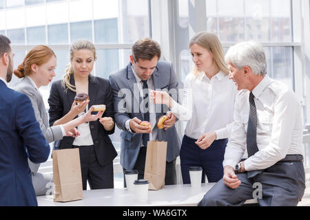 Business Leute zusammen mit Kaffeepause donuts Essen im Büro Stockfoto