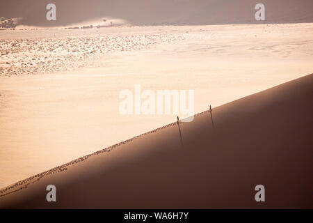 Zwei Menschen wandern auf einer Sanddüne in der Namibwüste, Namibia, Afrika Stockfoto