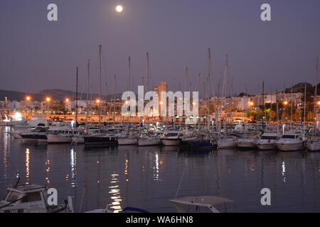 Vollmond über dem Hafen mit Yachten in der Marina im Vordergrund. Am frühen Morgen Licht. Stockfoto