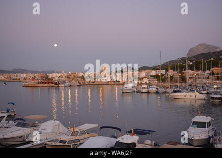 Vollmond über dem Hafen mit Yachten in der Marina im Vordergrund. Am frühen Morgen Licht. Stockfoto