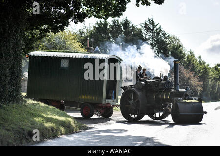 Eine Zugmaschine dampft, es hinterlässt Drusilla's Inn, in der Nähe von Horton, Dorset, als Dutzende von Dampf angetriebene Fahrzeuge bereiten den Weg in die Great Dorset Steam Fair, wo sie von Tausenden Fans feiern Dampfkraft ab 22. August Wochenende verbunden wird. Stockfoto