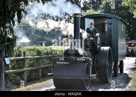 Eine Zugmaschine dampft, es hinterlässt Drusilla's Inn, in der Nähe von Horton, Dorset, als Dutzende von Dampf angetriebene Fahrzeuge bereiten den Weg in die Great Dorset Steam Fair, wo sie von Tausenden Fans feiern Dampfkraft ab 22. August Wochenende verbunden wird. Stockfoto