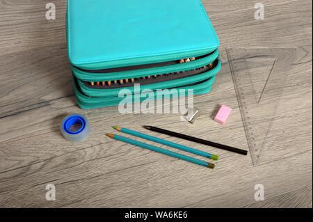 Drei Layer Federmäppchen auf hölzernen Tisch. Lineal, Anspitzer, Rolle, Dreieck, Lineal und Bleistift an der Seite. Hohe Betrachtungswinkel auf horizontalen Ima Stockfoto