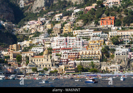 Blick von einem Boot aus auf die farbenfrohen Hotels und Häuser auf einem Hügel hoch über Positano an der Amalfiküste, Italien Stockfoto