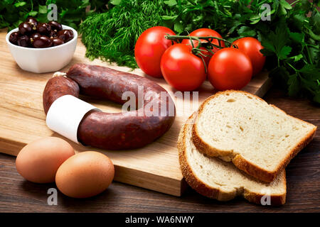 Türkische fermentierte Wurst auf Holztisch mit Holz Schneidebrett mit Eiern, Olivenöl, Petersilie und Tomaten. Türkischen Frühstück. Stockfoto