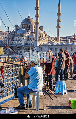 Istanbul, Türkei - 16 April, 2016 - Männer zu sozialisieren, wie sie Fische von einer Brücke mit der Blauen Moschee im Hintergrund Stockfoto