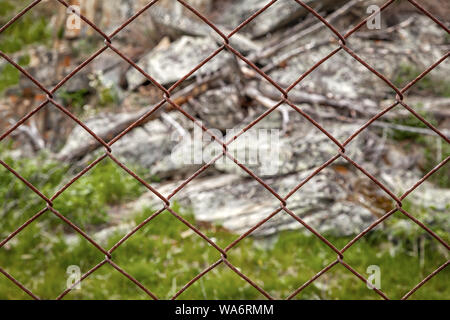 Close-up Grau Steine, einen kleinen Teil der Berge hinter dem Metal Bars. Das Konzept des Kampfes für den Umweltschutz Stockfoto