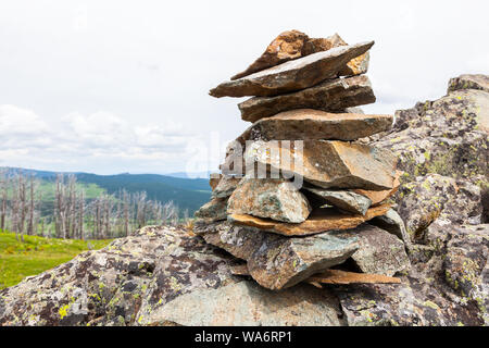 In der Nähe von Steinen, die von einer Klippe fiel, der sich aus einer Pyramide stehen vor dem Hintergrund der Berge und Wälder. Die Textur der grauen Stein, die ba Stockfoto