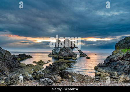 Bogen GEIGE ROCK PORTKNOCKIE Küste von Moray in Schottland am frühen Morgen farbige SONNENAUFGANG MIT EINEM BRUCH IN DEN WOLKEN SOMMER MITTE AUGUST Stockfoto