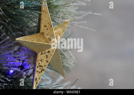 Glänzendes Gold Star hängen an einem eingerichteten Ferienwohnung Baum mit Beleuchtung Stockfoto