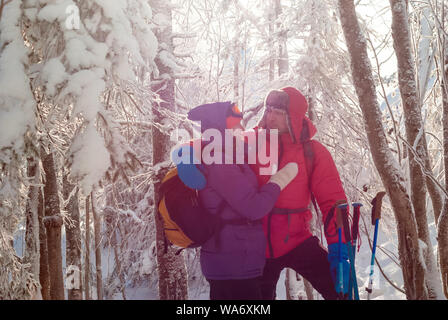 Mann und Frau Reisende schauen sich an, gegen die Sonne im Winter Wald auf einer sonnigen frostigen Tag Stockfoto