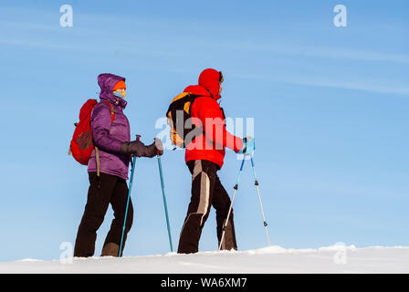 Mann und Frau Reisende gehen im Winter im Schnee gegen den Himmel Stockfoto