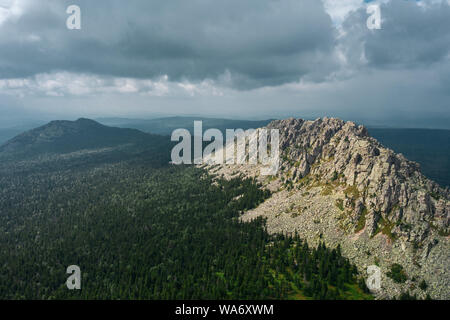 Luftaufnahme von Ural Natur. drohne Fliegen über den steilen steinigen Hang mit Nadel- und Laubwald Mischwald am Fuße des Berges. natiounal Park Stockfoto