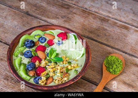 Smoothie Schale Matcha grüner Tee mit frischen Früchten, Beeren, Nüssen, Samen mit einem Löffel für gesunde vegane, vegetarische Ernährung Frühstück. Nach oben Schließen Stockfoto