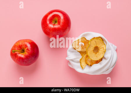 Hausgemachte sonnengetrockneten Bio crispy Apple Chips in Stoffbeutel, auf rosa Hintergrund mit frischen Apfel. Null Abfall, Kunststoff kostenloses Recycling Textil- Konzept. Co Stockfoto