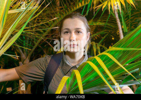 Junge Frau traveler im Dschungel unter Palmblättern portrait Stockfoto