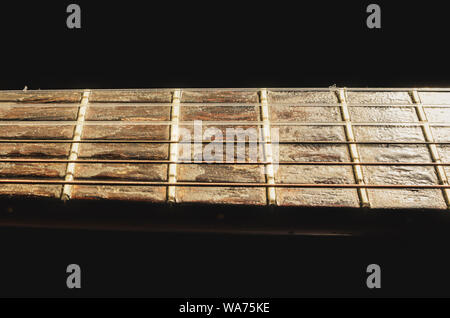 Isolierte Hals einer akustischen Gitarre auf der Horizontalen. Details der verschlissenen Holz- Ausschnitt. Ausschnitt eines alten Akustik Gitarre mit Bünden und Rusty nylon s Stockfoto