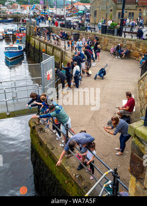 Urlauber, die im Sommer die Fischerei auf Krebse, die durch die Brücke im Hafen von Whitby, North Yorkshire England Großbritannien Stockfoto