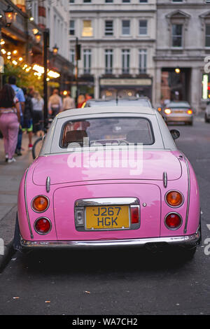 London, UK - August, 2019. Ein rosa im Retrostil Nissan Figaro in einer ruhigen Straße in der Nähe von Covent Garden in London geparkt. Stockfoto