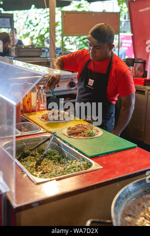 London, UK - August, 2019. Ein Mann der Vorbereitung einer Chicken wrap in einem Mexikanischen Straße Essen in Borough Market Stall. Stockfoto
