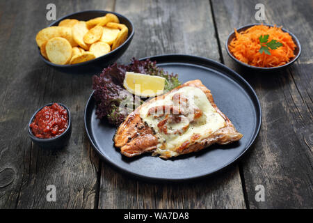 Fischfilet gebacken mit getrockneten Tomaten und Mozzarella, gebackene Kartoffeln und Salat. Stockfoto