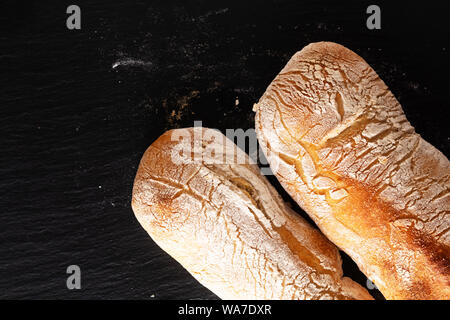 Essen Konzept hausgemachte Artisan im klassischen italienischen Stil Hefeteig Ciabatta Brot auf schwarzem Schiefer mit Kopie Raum Stockfoto