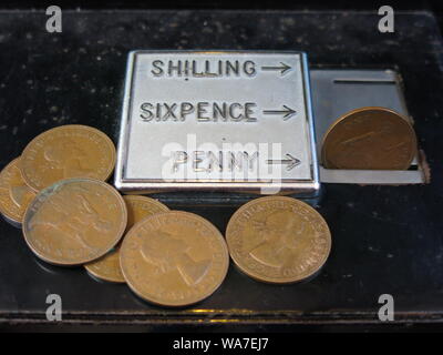 Nahaufnahme eines altmodischen Münze Steckplatz für Shilling, sixpence und Pennies in einem englischen Telefonzelle, mit einem der alten Cent Münzen auf der Seite stapeln. Stockfoto