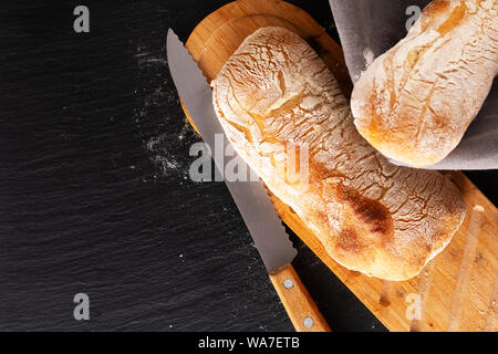 Essen Konzept hausgemachte Artisan im klassischen italienischen Stil Hefeteig Ciabatta Brot auf schwarzem Schiefer mit Kopie Raum Stockfoto