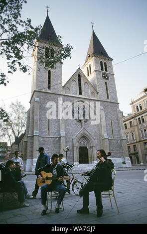 11. Mai 1993 während der Beladung von Sarajevo: Der 'Cellist von Sarajevo', Vedran Smailović, tritt mit einem gitarrenspielenden Freund vor der Kathedrale des Heiligen Herzens auf. Stockfoto