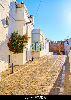 Marques de Tamaron Straße, eine typische Straße der weiß getünchten Wänden von Vejer de la Frontera Innenstadt mit La Segur Tor im Hintergrund. Vejer de la Fr Stockfoto