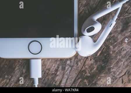 Nahaufnahme eines Smartphones mit angeschlossenen Kopfhörern auf einem Holzoberfläche Stockfoto