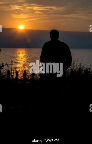 Ein Mensch braucht Zeit, den Sonnenuntergang über dem Lake Michigan zu beobachten und den Frieden und die Ruhe genießen Stockfoto