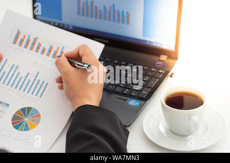 Geschäftsfrau Kaffee, während mit Laptop auf dem Schreibtisch Stockfoto