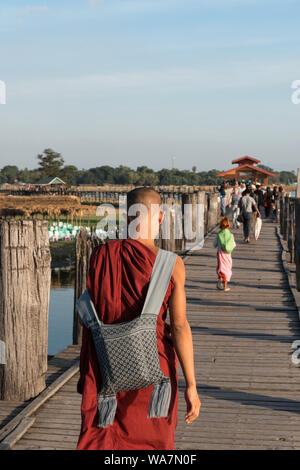 MANDALAY, MYANMAR - 03. Dezember 2018: Vertikale Bild der birmanischen Mönche gehen über den Holz- U-Bein Brücke, die ist eine touristische Attraktion von M Stockfoto