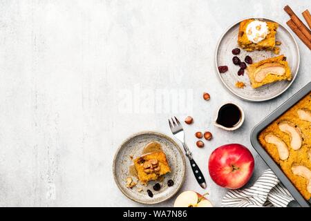 Apple Pumpkin Spice Kuchen schneiden in den Quadraten. Auf grauem Beton strukturierten Hintergrund. Ansicht von oben. Herbst Komfort essen Kuchen Rezept Stockfoto