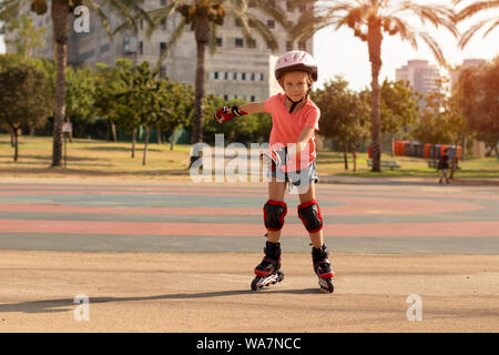 Kind auf Inline Skates in Park. Kinder lernen roller blades zu Skate Stockfoto