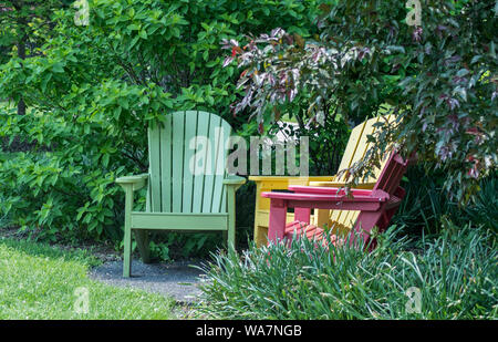 Bunte Adirondack Stühle in einem Garten Stockfoto