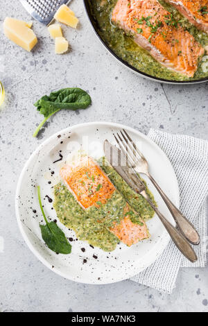 Gegrillter Lachs mit Spinat und Knoblauch Sauce auf einer Platte, Ansicht von oben Stockfoto