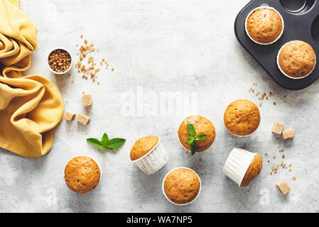 Vanille Karamell Muffins in Pappbechern auf grauem Beton Hintergrund. Tabelle Ansicht von Oben. Kopieren Sie Platz für Text Stockfoto