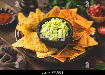 Guacamole mit Mais Tortilla Chips, Nachos auf hölzernen Tisch Hintergrund Stockfoto