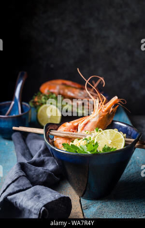 Eine Schüssel instant Chinesische Nudeln mit grünen Zwiebeln, red hot chili peppers, und Garnelen auf einem dunklen rustikalen Hintergrund Stockfoto