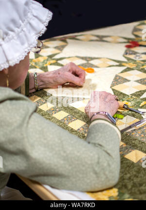 März 17, 2019 Indiana USA Zucker camp Tage Ereignis; eine Frau in Tracht beteiligt sich an einem altmodischen Quilting Bee Stockfoto