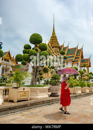 Bangkok, Thailand - Juni 2019: Nicht identifizierte asiatische Frau in Rot, die einen Regenschirm hält und den Königspalast besichtigen kann Stockfoto